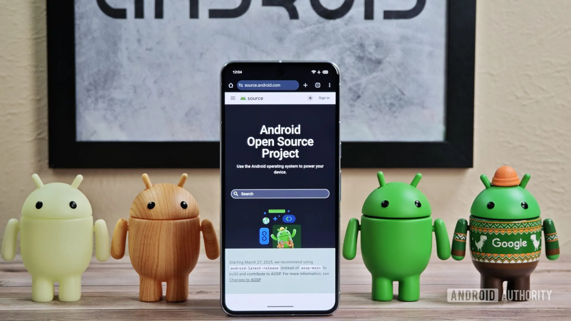 Android_figures_standing_around_Pixel_phone_with_AOSP_home_page_showing-1920w-1080h.jpg